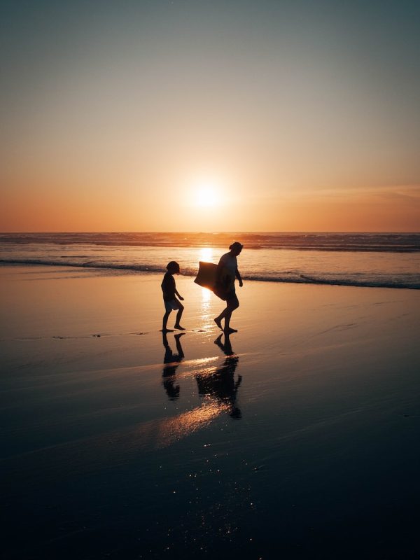 2 men walking on beach during sunset