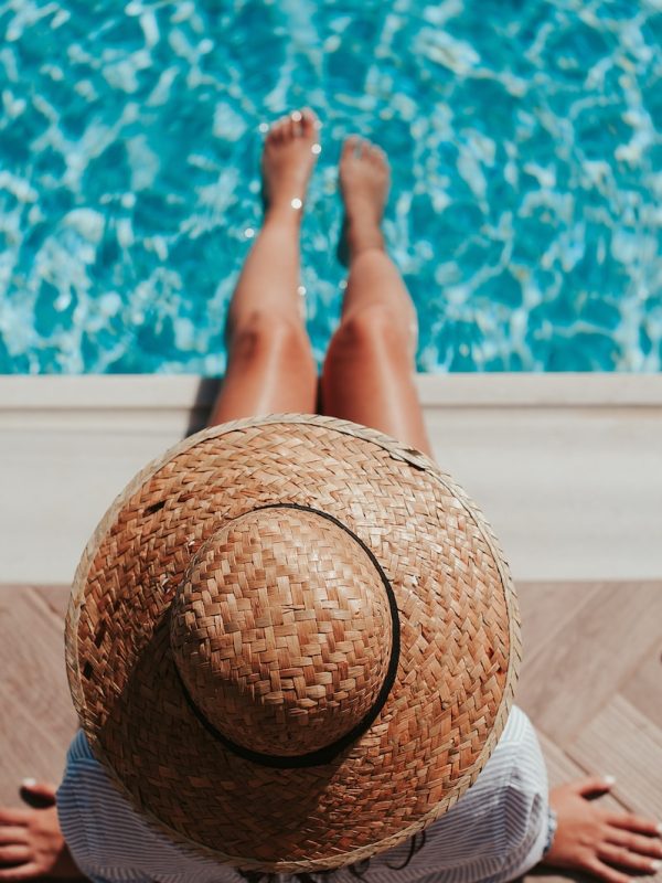 woman sitting on poolside setting both of her feet on pool